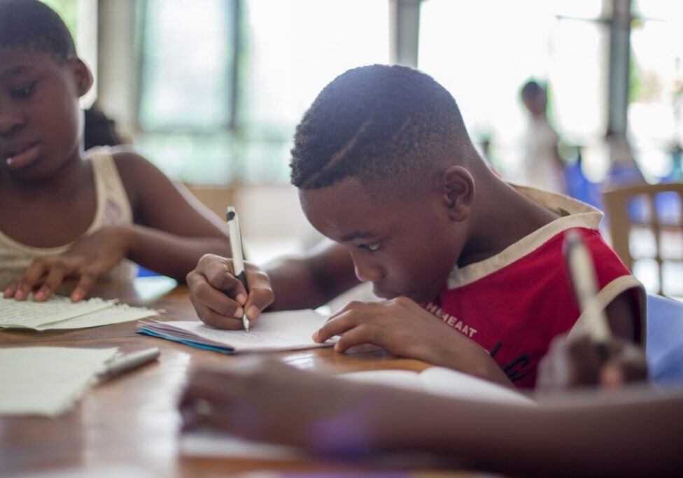 boy writing on printer paper near girl